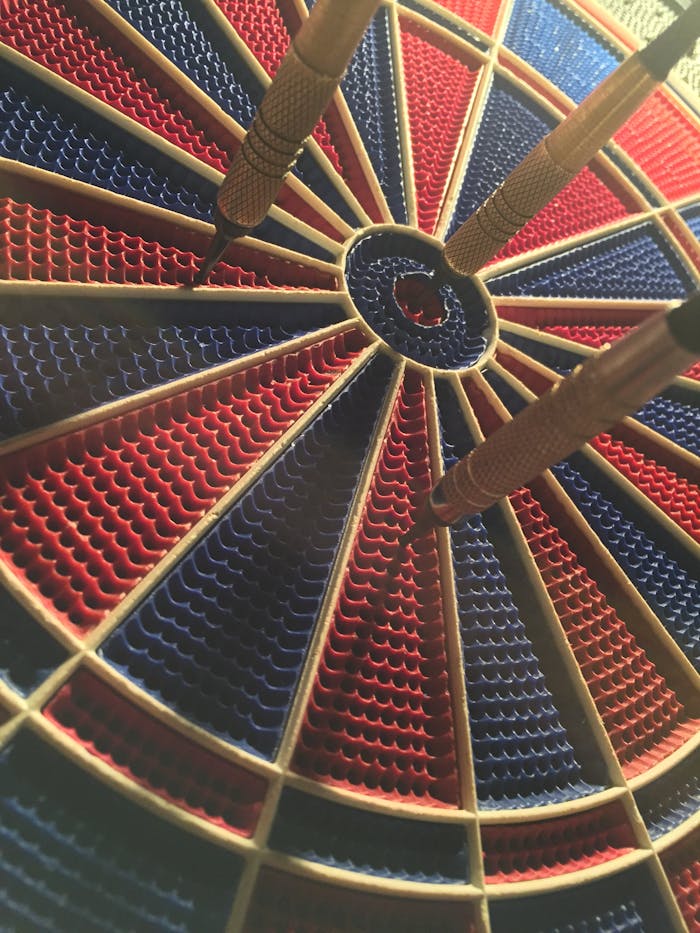 pexels-photo-416816 A detailed view of a dartboard with darts in the bullseye, showcasing a competitive sports moment.